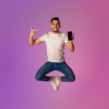 Young Arab Man Jumps in Neon Light Showcasing Smartphone for App Advertisement