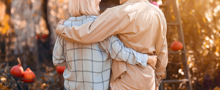 Couple Enjoying Sunset in Autumn Garden Surrounded by Pumpkins and Colorful Leavesの写真素材