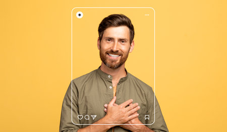 Smiling Man Poses With Hands Over Heart Against a Yellow Background in Social Media Themeの写真素材