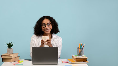 Happy Black Female Taking a Coffee Break While Studying at Her Desk