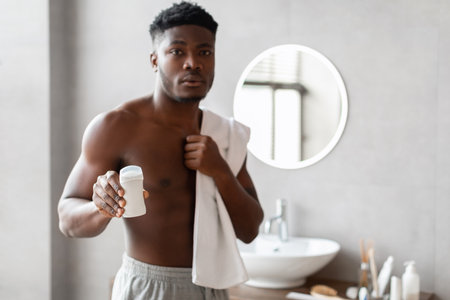 Shirtless Man Demonstrates Antiperspirant Stick in Modern Bathroom Settingの写真素材