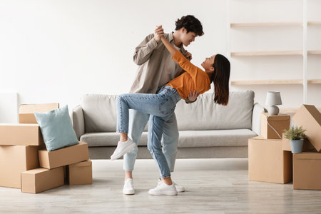 Young Couple Enjoys Dancing Together in Their Home During Moving Day Celebrationの写真素材