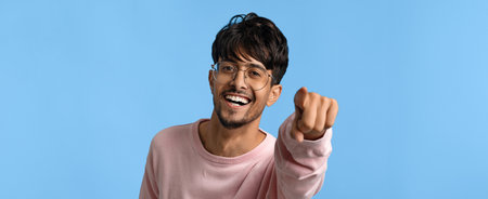Young Man Smiling and Raising His Fist Against a Blue Background in a Casual Setting
