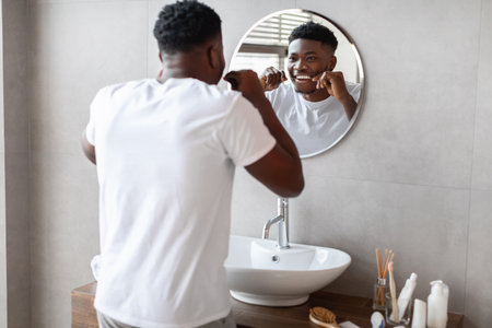 Young Man Practices Daily Oral Hygiene With Floss in Modern Bathroom Settingの写真素材