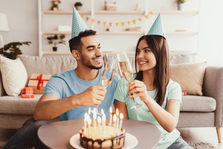 Couple Celebrates Birthday With Cake and Toasts in Cozy Living Room Settingの写真素材