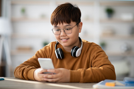 Chubby Asian Boy Enjoys Mobile Gaming at Home With Wireless Headset Onの写真素材