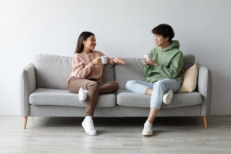 Young Couple Enjoying Coffee and Conversation on a Cozy Weekend at Homeの写真素材