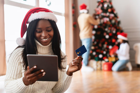 Smiling Lady Shopping Online at Home During Christmas Season With Credit Card in Handの写真素材