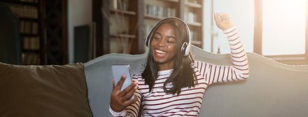 Young Woman Enjoying Music at Home While Using a Smartphone in the Afternoon