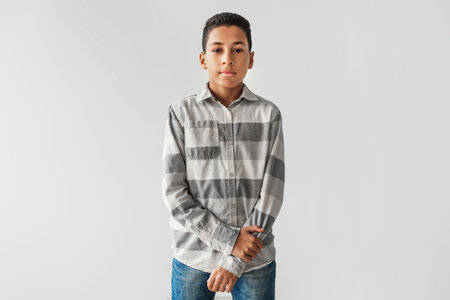 Serious Black Preteen Boy Looking Confidently at the Camera in Casual Clothes Over Gray Backgroundの写真素材