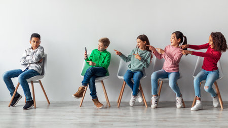 Kids Laughing at an African Boy While Using a Smartphone in a Classroom Settingの写真素材