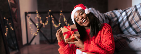 Joyful Woman in Red Sweater Celebrating Christmas With Gifts at Homeの写真素材