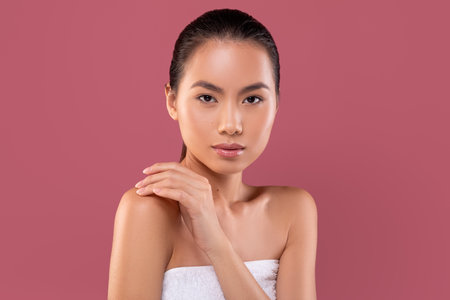 Sensual Korean Lady Enjoying Her Beauty Routine With Glowing Skin in Purple Studio Settingの写真素材