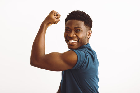 Young Man Flexing Muscles With a Big Smile in a Bright Studio Setting