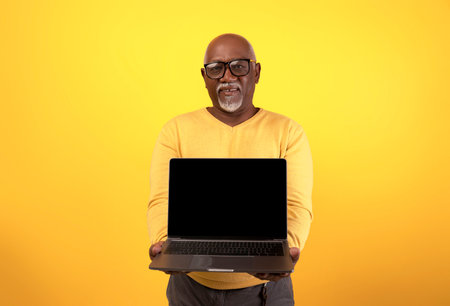 Senior Black Man Displays Laptop Computer With Blank Screen for Website Advertisementの写真素材