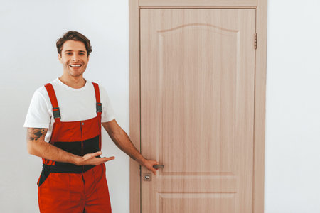 Smiling Worker Showcasing a New Wooden Door in a Modern Interior Settingの写真素材