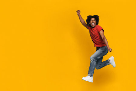 Young Man Joyfully Jumping Against Bright Yellow Background in Casual Outfit