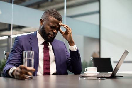 Sad black manager holding glass of water, office interiorの写真素材