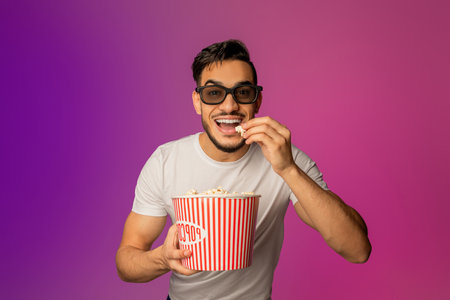 Young Arab Man Enjoying Popcorn While Watching a Movie in 3D Glasses at the Cinema