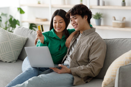 Happy Asian Family Enjoys Online Shopping Together on a Cozy Sofa at Homeの写真素材