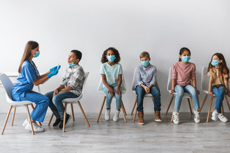 Nurse Performs PCR Test on Preteen Boy in Clinic While Testing Group of Children Indoorsの写真素材