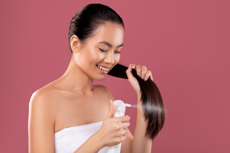 Happy Young Woman Styles Her Long Hair With Hair Spray in Purple Studio After Morning Showerの写真素材