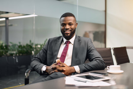 Cheerful black guy CEO sitting at conference hallの写真素材