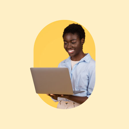 Smiling Woman Working on Laptop in a Bright Yellow Setting With a Joyful Expressionの写真素材