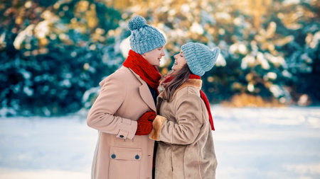 Winter Couple Enjoying a Snowy Day in the Park While Bundled up in Warm Clothesの写真素材