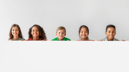Multicultural Children Smiling and Holding a Blank Poster in a Gray Studioの写真素材