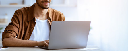 Man Using Laptop While Sitting at Table in Bright Room During Daytime Hours