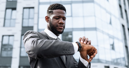 Business Professional Checks Watch Outside Modern Office Building During Daytimeの写真素材