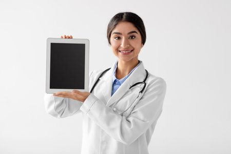 Attractive Young Indian Female Medical Worker With Digital Tablet in a Uniform on White Backgroundの写真素材