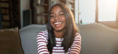 Smiling Woman Sitting on a Couch in a Cozy Room With Bookshelves in the Background