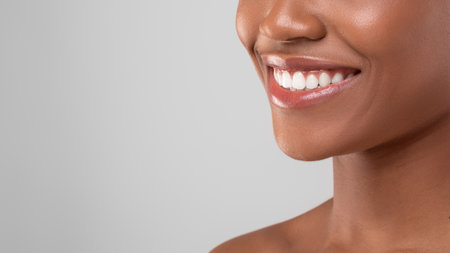 Bright Smile of a Woman Showcasing Healthy Teeth and Glowing Skin Against a Neutral Backgroundの写真素材