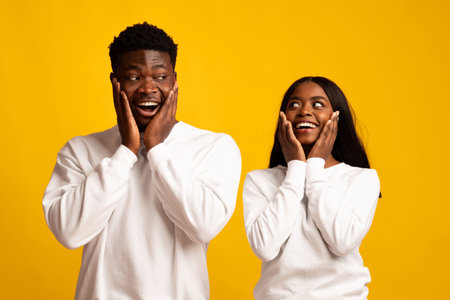 Surprised Couple Enjoying a Joyful Moment Against a Bright Yellow Backgroundの写真素材
