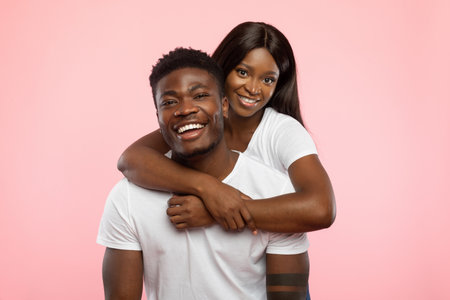 Young Couple Shares a Joyful Embrace in Studio With Pink Backgroundの写真素材
