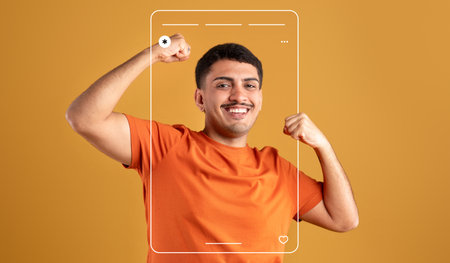 Happy Young Man Celebrating Success in a Bright Orange Shirt Against a Colorful Background