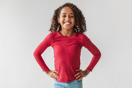 Positive African American Girl Posing Confidently With Hands on Hips Against a Gray Backgroundの写真素材