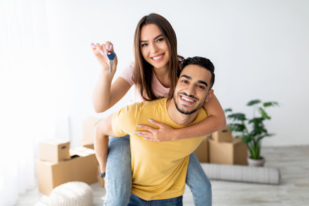 Young Couple Celebrates New Home With Key in Hand in a Bright, Unpacked Living Room