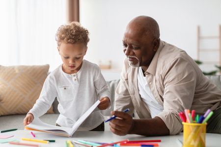 Little Boy Shares His Drawings With Grandpa While They Create Art Together at Homeの写真素材