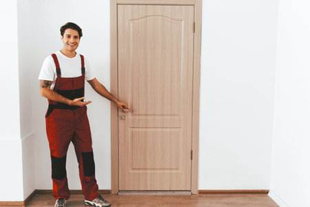 Man Showing New Wooden Door in Modern Interior Space With Bright Lightingの写真素材