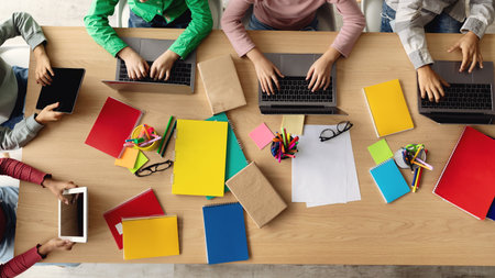 School Kids Collaborate Using Laptops at a Bright Desk During Modern Classroom Activityの写真素材
