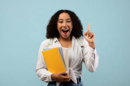 Excited Young Woman Discovers Inspiration While Studying With Colorful Materials in Blue Settingの写真素材