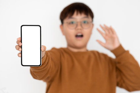 Shocked Teenage Boy Shows Empty Smartphone Screen While Recommending New Appの写真素材