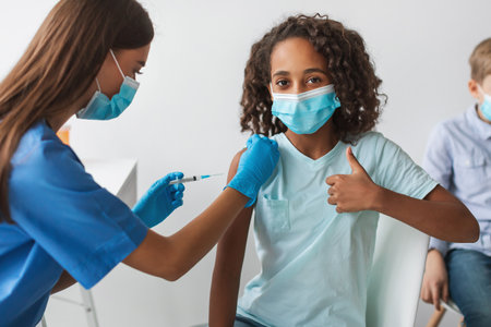 Black Girl Gives Thumbs up While Getting Covid-19 Vaccine in Clinicの写真素材