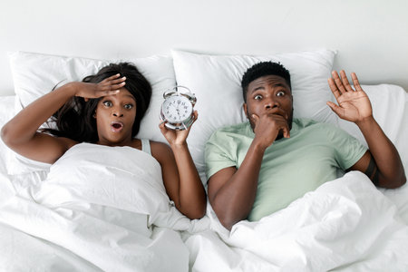 Couple Startled by Alarm Clock in Bed, Showing Surprise and Urgency in a Morning Moment