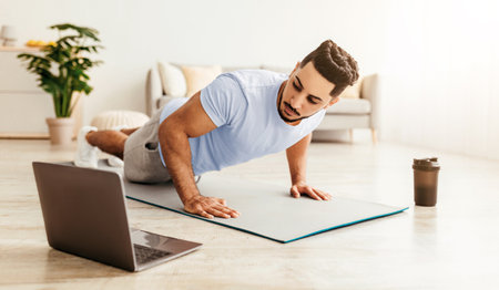 Man Exercising at Home With Laptop and Coffee in a Bright Living Room Setting
