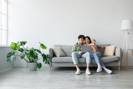 Young Couple Shopping Online Together From Their Cozy Living Roomの写真素材