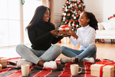 Happy Black Family Exchanging Christmas Presents in Cozy Living Room Settingの写真素材